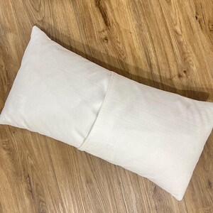 May include: A white rectangular pillow with a zipper closure on one side.