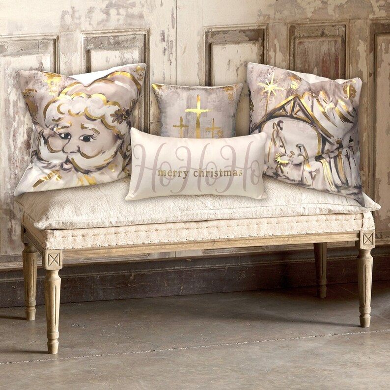 May include: Four decorative throw pillows with a Christmas theme. The pillows feature a Santa Claus, a nativity scene, and two crosses. The pillows are arranged on a white bench with a distressed wood finish. The text "Ho Ho Ho merry christmas" is printed on one of the pillows.