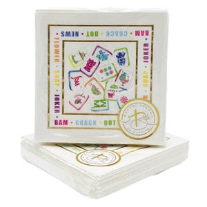 May include: White square napkins with a gold border and colorful illustrations. The napkins feature a gold seal with the text "RACHEL BROOKS 24 NAPKINS". The napkins have the words "FLOWER SOAP JOKER" and "BAM CRACK DOT NEWS" printed on them.