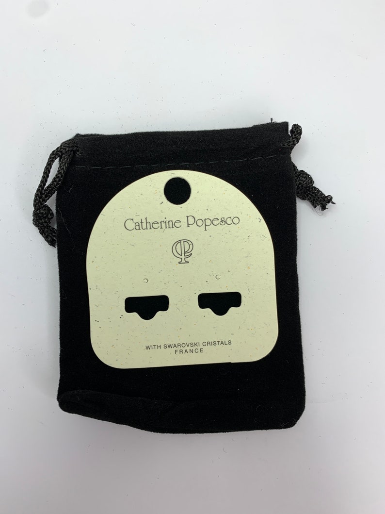 以下が含まれることがあります： 黒いベルベットのジュエリーポーチ、巾着開閉式。ポーチの中には、薄いベージュ色のイヤリングディスプレイカードが入っています。カードには「Catherine Popesco」と「WITH SWAROVSKI CRISTALS FRANCE」と書かれています。