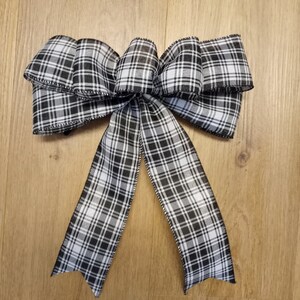 May include: A black and white plaid bow with a satin finish. The bow is tied with a loop and tails.