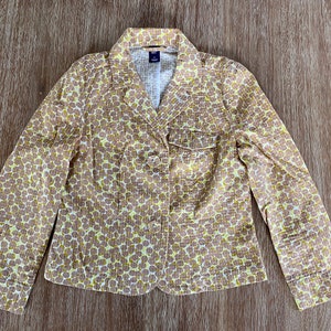 May include: A yellow and brown patterned blazer with a button closure and a pocket on the left side.