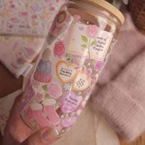 May include: A clear glass tumbler with a bamboo lid and straw, decorated with pink and white stickers. The stickers feature roses, hearts, and text that reads "Hockey Romance Girlie" and "Lover of Fictional Hockey Players."
