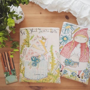 May include: Two book covers with illustrations of a girl in a red hood and a wolf in the woods. The text on the cover reads "So glad you're here".