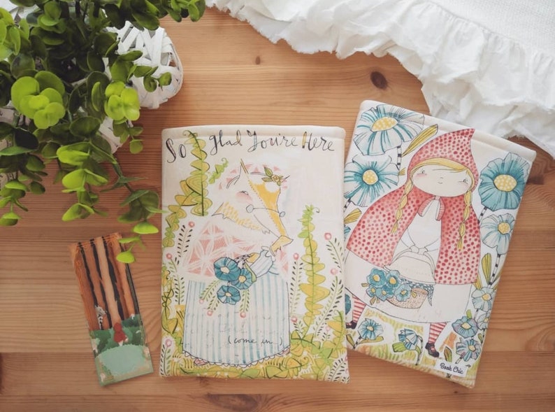 May include: Two book covers with illustrations of a girl in a red hood and a wolf in the woods. The text on the cover reads "So glad you're here".
