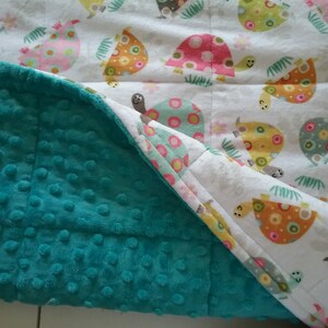 May include: A turquoise blue minky fabric blanket with a white fabric side featuring a repeating pattern of colorful turtles with polka dots.