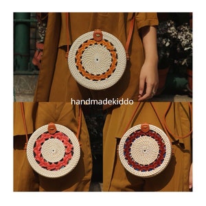 Puede incluir: Bolsos redondos de rat&aacute;n tejido con correas de cuero. Los bolsos presentan intrincados patrones en naranja, rojo y azul. Los bolsos se muestran sobre un fondo marr&oacute;n. El texto "handmadekiddo" es visible.