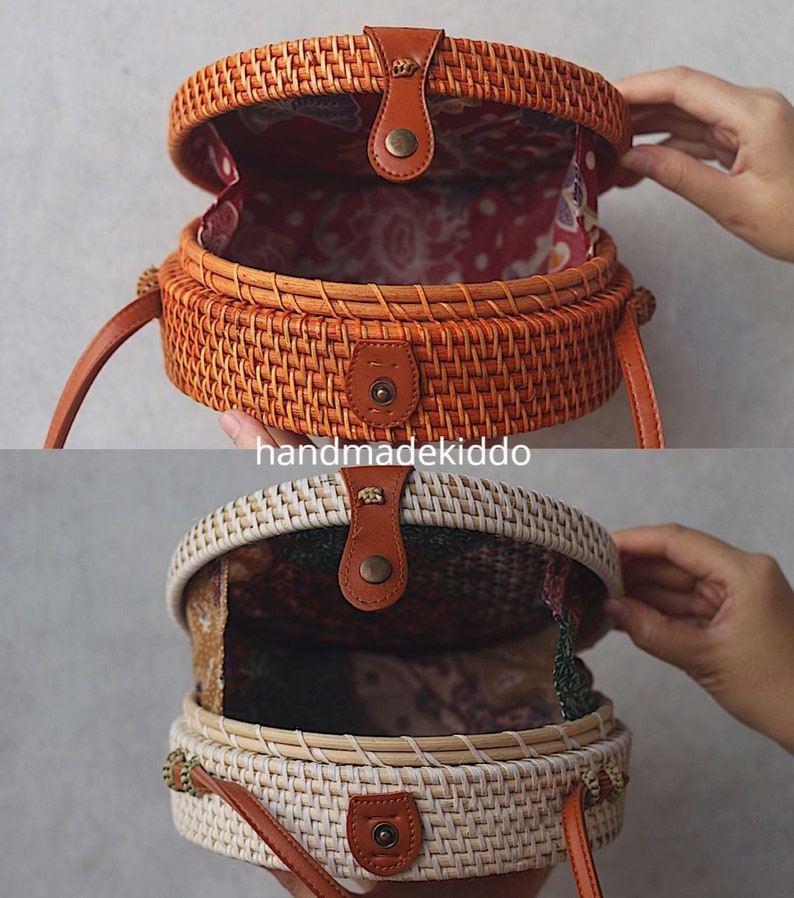 May include: Two round woven rattan bags with leather straps and closures. The top bag is brown and the bottom bag is white.