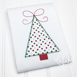 May include: White fabric with an embroidered Christmas tree design. The tree is green with red, green, and silver polka dots. A red bow is at the top, and a red square forms the tree trunk.