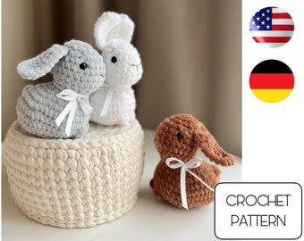 May include: Crochet pattern for three amigurumi bunny toys. The bunnies are gray, white, and brown. The pattern includes instructions for making the bunnies and a basket.