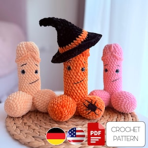 May include: Three handmade crochet figures in shades of peach, orange, and pink, each with a smiling face. The central figure is orange and wears a black and orange witch hat. A small black spider is crocheted on the orange figure.