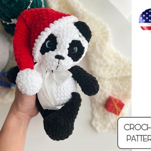 May include: Crochet pattern for a panda bear wearing a red Santa hat with white trim. The panda is holding a white ribbon in its paws.