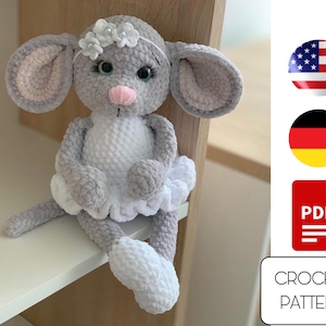 May include: Crochet pattern for a gray and white mouse wearing a white tutu. The pattern is available as a PDF download. The image also includes flags for the United States and Germany.