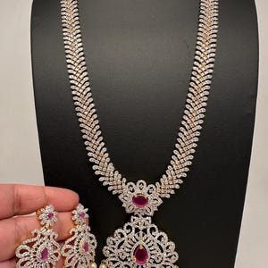 May include: A white ceramic mug with a black handle and the text "But First, Coffee" in a bold, black font. The mug is set against a blurred background, suggesting a cozy setting.