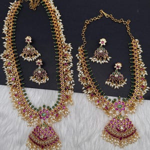 May include: Two gold-toned necklace and earring sets featuring intricate metalwork, embedded with small pink and green stones. Each piece is accented with clusters of tiny white seed pearls and dangling pearl beads, creating a detailed, layered appearance.