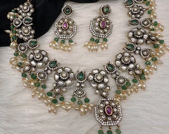 May include: An elaborate necklace and earring set with a floral design, clear and emerald-green gemstones, and small pearl accents. The necklace and earrings have a silver-tone metal finish and a gold-tone chain.