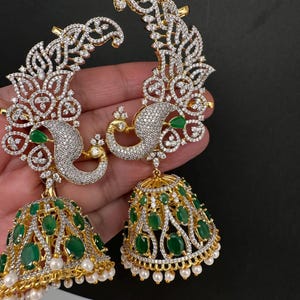 May include: A white ceramic mug with a black handle and the text "But First, Coffee" in a bold, black font. The mug is set against a blurred background, suggesting a cozy setting.