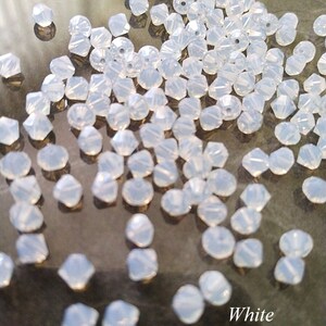 May include: A large quantity of white opal bicone beads. The beads are faceted and have a pearlescent finish.