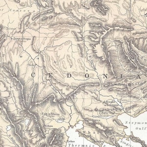 May include: An antique map of the Macedonia region, rendered in grayscale. The map shows detailed geographical features, including mountains and rivers, with text labels indicating cities and bodies of water. The map is a historical document, with fine line work.