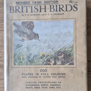 May include: A vintage book titled "British Birds" from 1938, featuring a cover illustration of birds in a natural habitat. The cover is tan with black and blue text, and the book promises 200 plates in full color with concise descriptions.