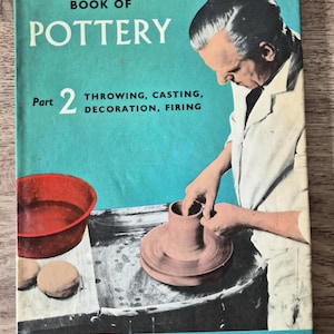 May include: A rectangular book titled The Beginner's Book of Pottery Part 2 Throwing, Casting, Decoration, Firing by Harold Powell. The cover features a teal background with an illustration of a person shaping clay on a pottery wheel.