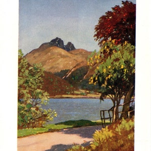 May include: A painting of a mountain range with a lake in the foreground. The mountain range is brown and green, and the lake is blue. There are trees on the left side of the image, and a red-leaved tree on the right side of the image. The text "The Cobbler seen across Loch Long" is at the bottom of the image.