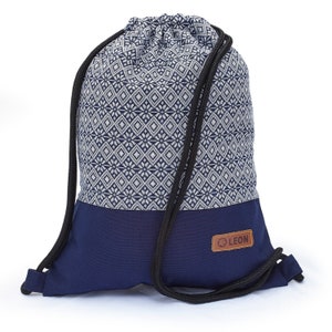 May include: A blue drawstring bag with a white and blue geometric pattern. The bag has a brown leather tag with the word "LEON" on it.