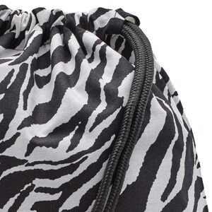 Op de afbeelding: Close-up van een zwart-witte zebraprint trekkoordtas met zwarte trekkoorden.