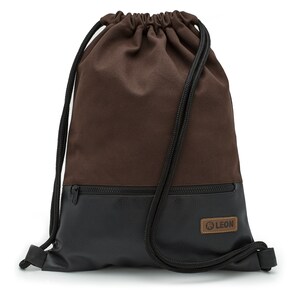May include: Brown drawstring backpack with a black faux leather bottom and a zippered pocket. The pocket has a brown leather patch with the word "LEON" in white lettering.