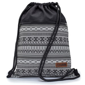 Könnte beinhalten: Schwarze Kordelzugtasche mit einem geometrischen Muster in Weiß und Schwarz. Die Tasche hat eine Reißverschlusstasche und ein braunes Leder-Etikett mit dem Wort "LEON" darauf.