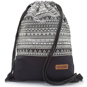 May include: A black and white patterned drawstring backpack with a black base and black rope straps. The upper portion features a repeating geometric design. A small brown leather patch with the word "LEON" is sewn on the lower front.