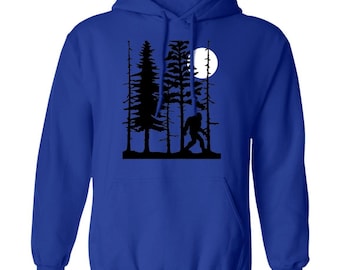 Peut inclure: Un sweat à capuche bleu royal avec une silhouette noire de Bigfoot marchant dans une forêt avec une pleine lune en arrière-plan.