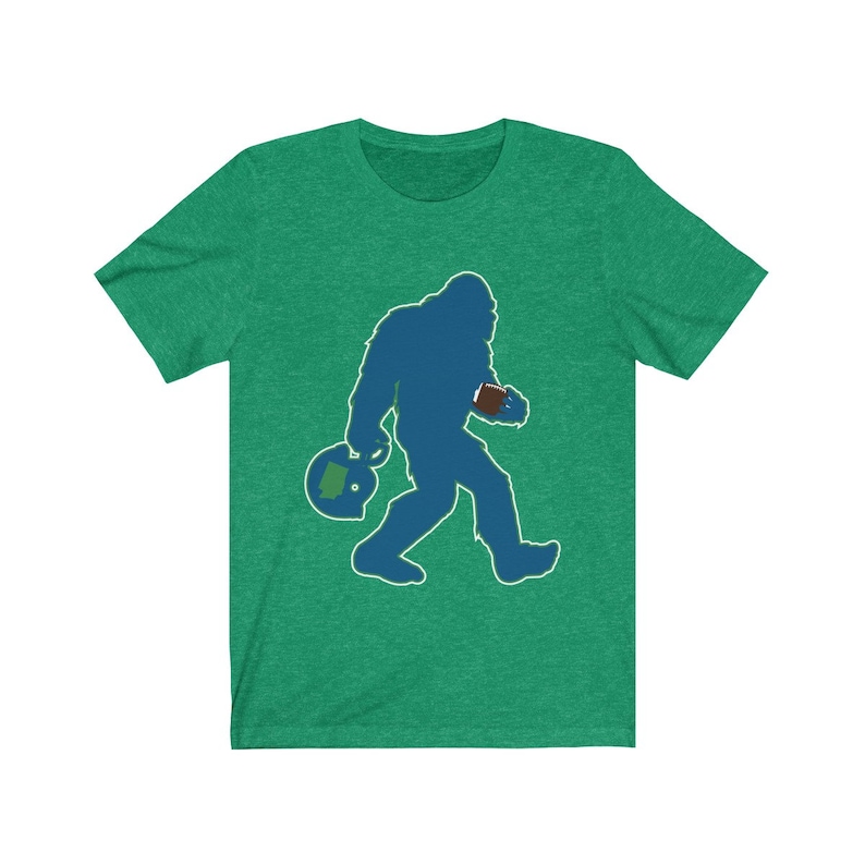 K&ouml;nnte beinhalten: Gr&uuml;nes T-Shirt mit einer blauen Silhouette eines Bigfoots, der einen Football und einen Helm tr&auml;gt.