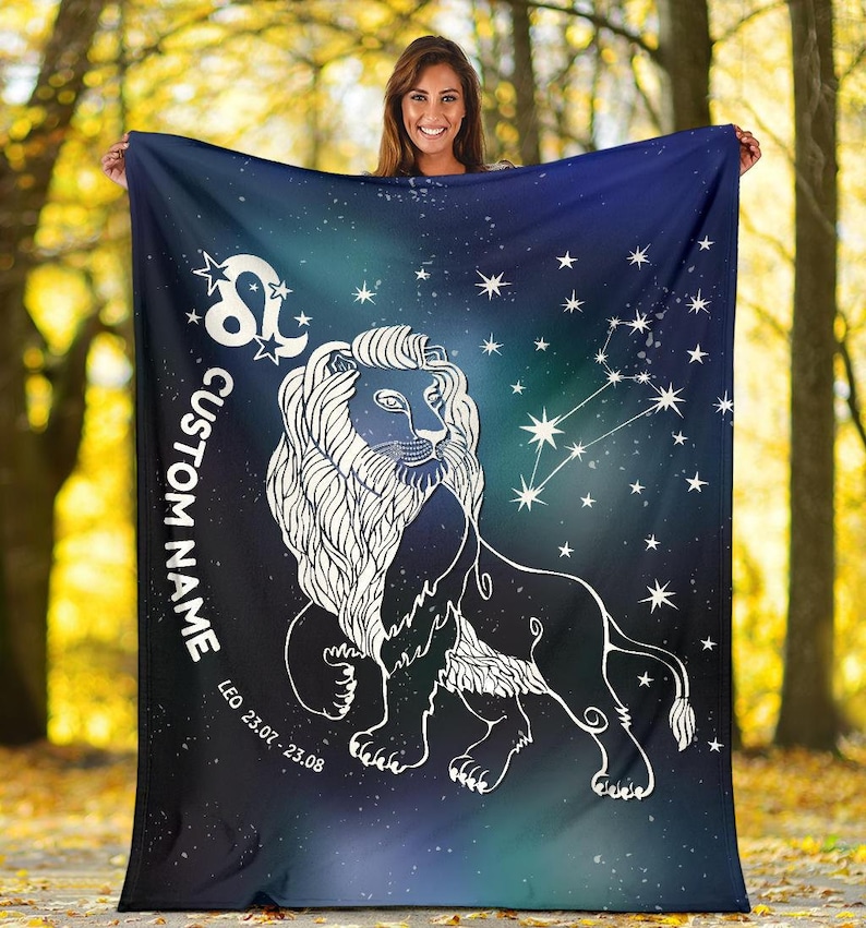 May include: A blue and green fleece blanket with a white outline of a lion and the constellation Leo. The blanket has a starry background and the text "CUSTOM NAME" and "LEO 23.07 - 23.08" printed on it.