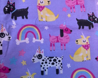 Puede incluir: Tela morada con un patrón repetido de perros con cuernos de unicornio. Los perros son de varios colores y patrones, incluyendo negro, blanco, rosa y amarillo. También hay arcoíris y estrellas en la tela.