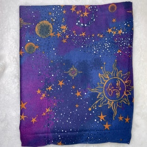 May include: Purple and blue fabric with a celestial pattern featuring gold stars, a sun, and moons. The fabric has a watercolor-like effect.
