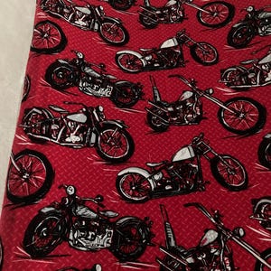 May include: Red fabric with a repeating pattern of black and white motorcycle illustrations. The motorcycles are drawn in a vintage style with detailed engine and wheel designs.