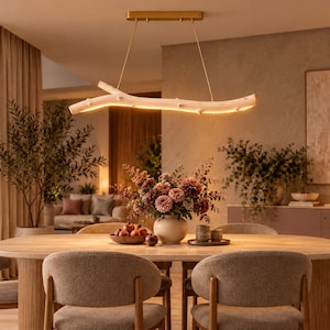 May include: A linear pendant light fixture featuring a light-colored wooden branch design suspended by thin wires from a rectangular gold-toned ceiling mount, with an integrated LED light strip running along the underside of the branch.