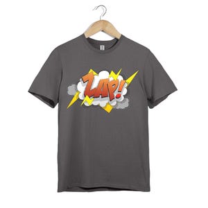 Könnte beinhalten: Dunkelgraues T-Shirt mit einem Comic-Grafik "ZAP!". Die Grafik zeigt das Wort "ZAP!" in Rot und Orange, schwarz umrandet, mit gelben Blitzen und einem weißen Wolkenhintergrund.