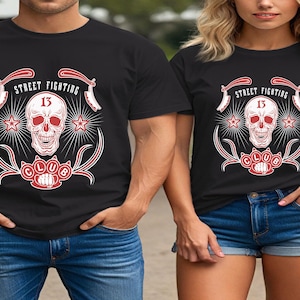 May include: Black t-shirts with a red and white graphic design. The design features a skull, the number 13, stars, and the words "Street Fighting Club". The shirts are worn with blue denim.