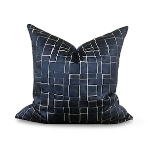 May include: A navy blue throw pillow with a white geometric pattern. The pillow is made of a soft, velvet fabric.