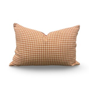 May include: A long rectangular pillow with a brown and white houndstooth pattern.