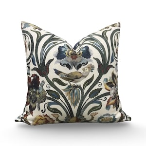 May include: Decorative throw pillow with a floral and bird pattern. The pillow features a cream background with a design of blue, green, and brown flowers and a bird. The pillow is square and has a soft, inviting appearance.
