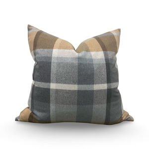 May include: A square decorative pillow with a plaid pattern in shades of gray, beige, and white. The pillow is a soft, neutral accent for a bed or sofa. The pillow is approximately 18 inches square.