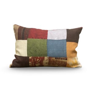 May include: A rectangular pillow with a patchwork design. The pillow is made of different fabrics in shades of brown, red, green, blue, and beige. The fabrics are sewn together in a grid pattern.