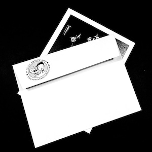 May include: A black and white image of a greeting card set. The set includes a white envelope with a printed logo and a black and white photograph. The logo features two cartoon figures and the text "no filter greeting cards". The website address is also printed on the envelope.