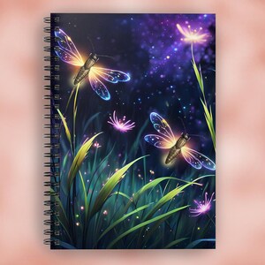 May include: Spiral-bound notebook featuring a fantasy illustration of glowing dragonflies and flowers in a field. The artwork has a dark blue and purple background with sparkling stars and vibrant green grass.