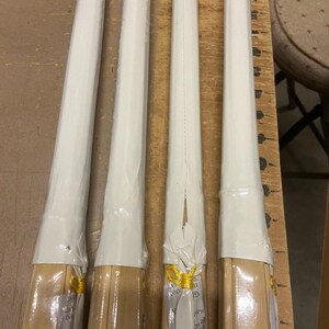 May include: Four wooden sticks wrapped in white plastic with gold ribbon. The sticks are bundled together and have a white label with black text.