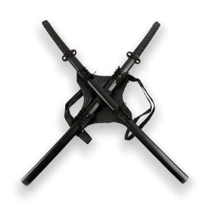 May include: Two black katana swords crossed and strapped to a black leather harness. The swords have black braided handles and are secured with straps.