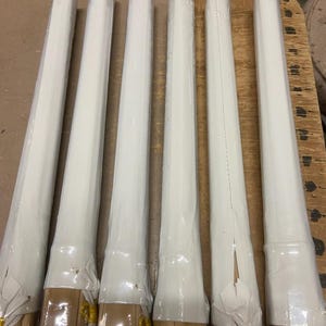 May include: Six wooden dowels wrapped in white paper with gold accents. The dowels are bundled together and ready to be used for crafts or other projects.